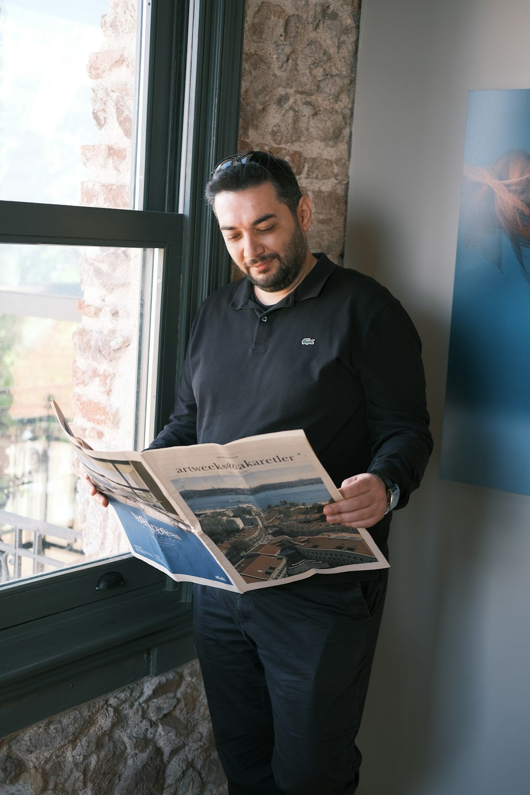a man standing in front of a window reading a newspaper