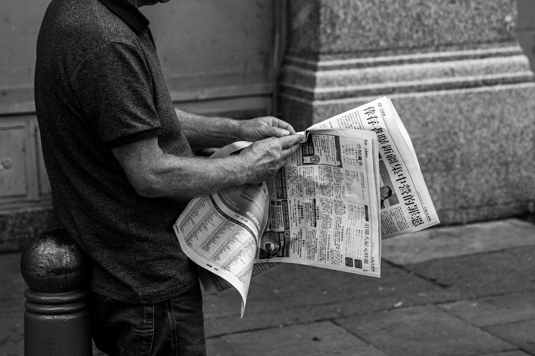 grayscale photo of man holding newspaper