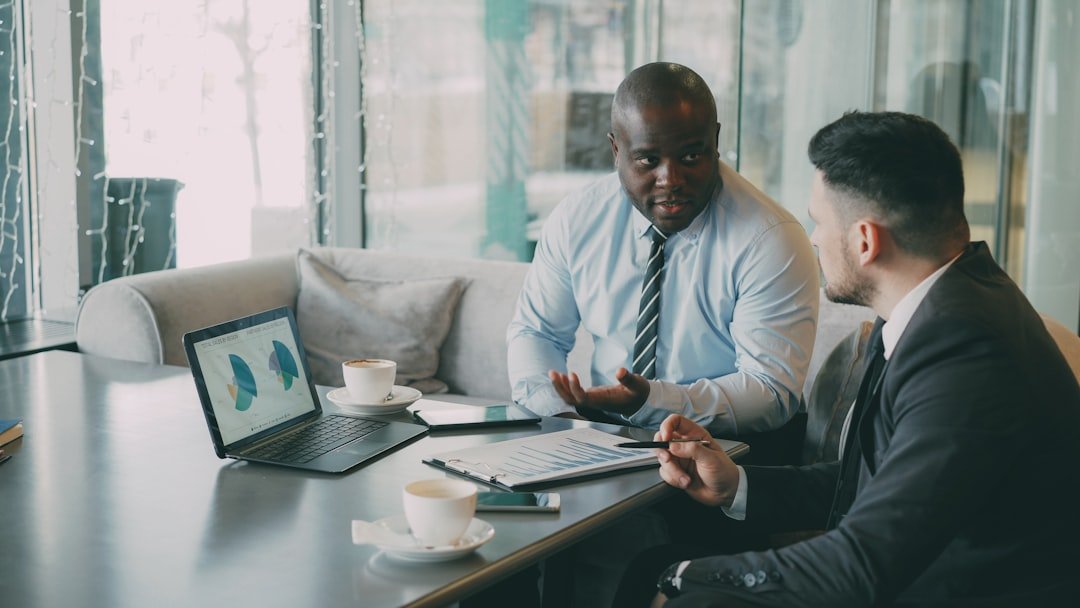 Two businessmen discussing charts on a laptop.