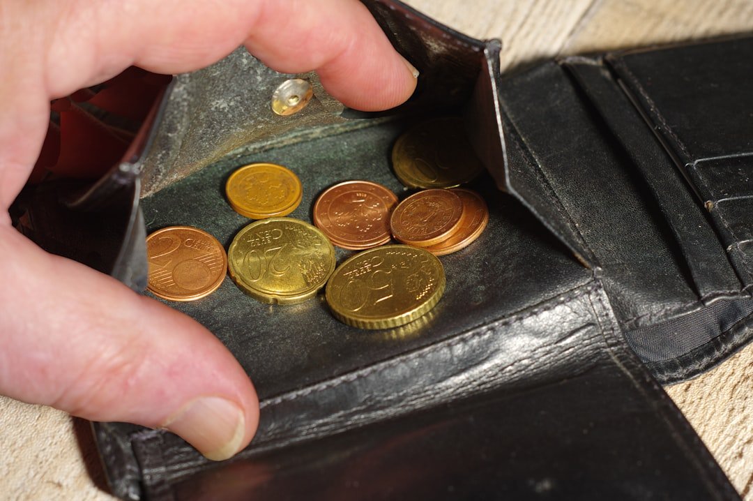 Hand placing coins into a black leather wallet.
