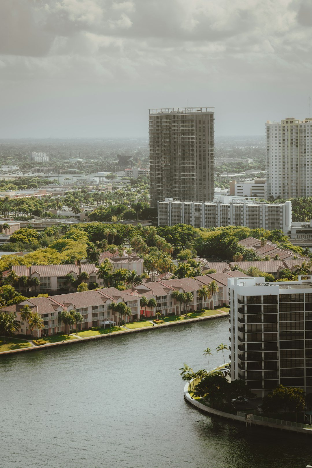 Waterfront buildings and lush green trees by canal.