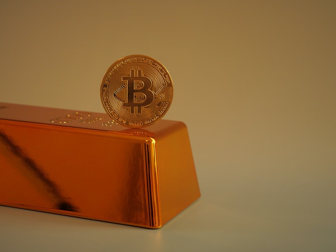 Bitcoin coin resting on a gold bar.