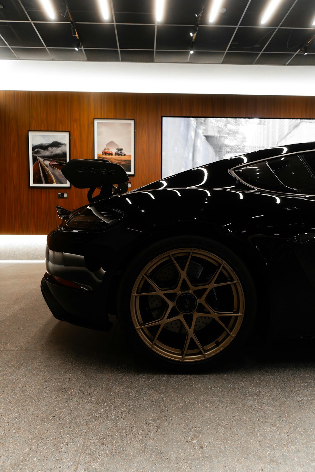 Black sports car with gold wheels in showroom