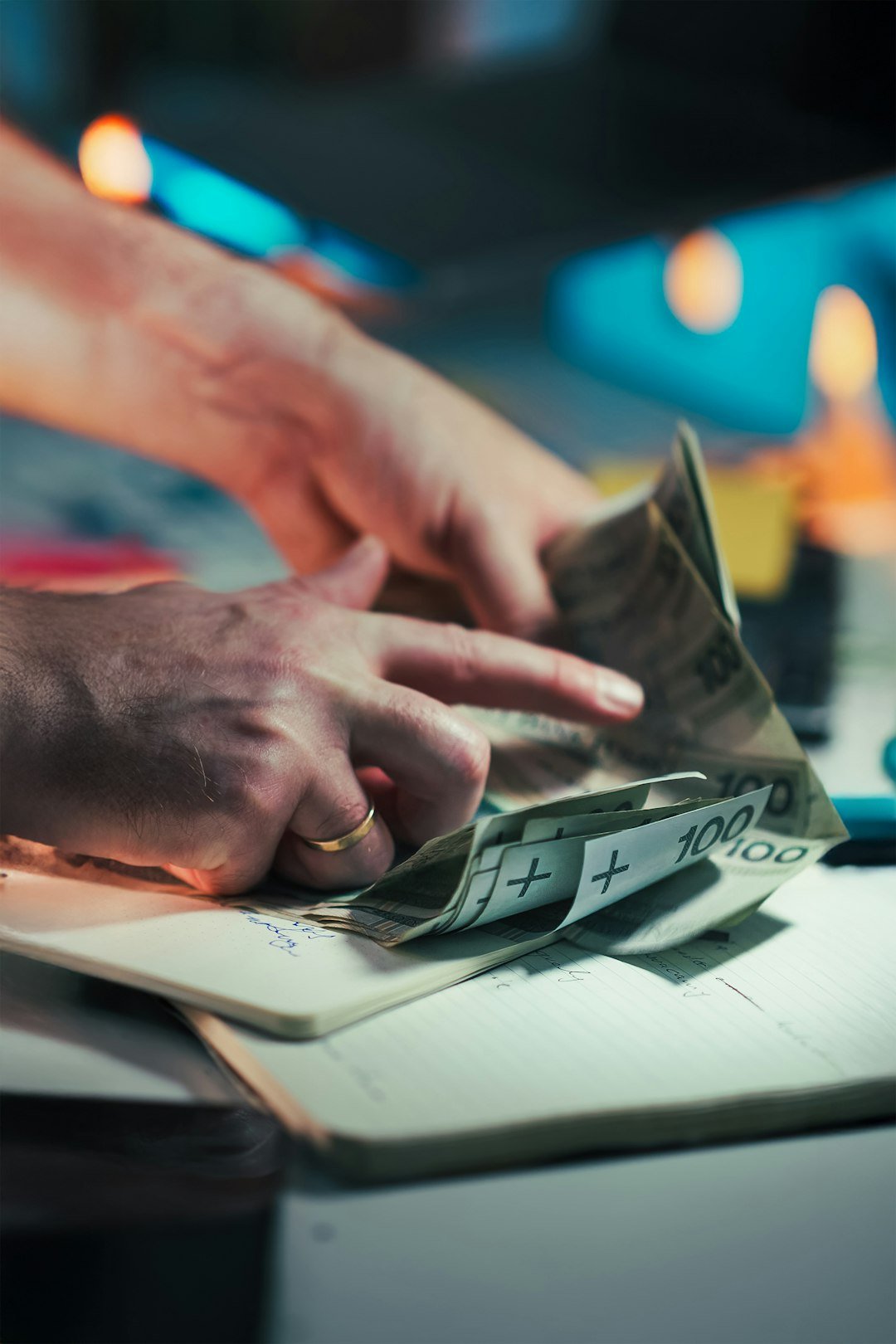 Hands counting polish banknotes on a notebook.