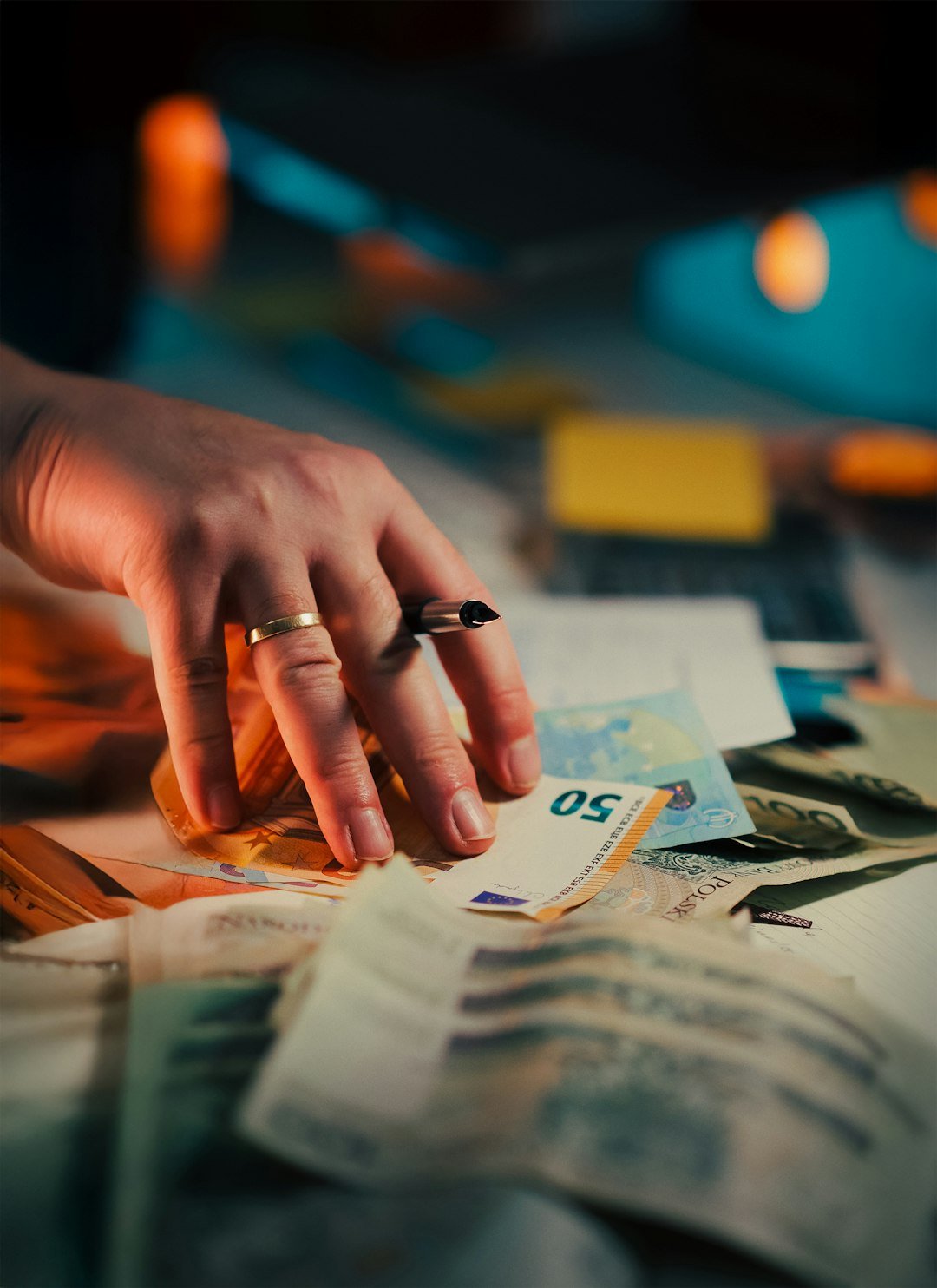 Hand reaching for a stack of euro banknotes.