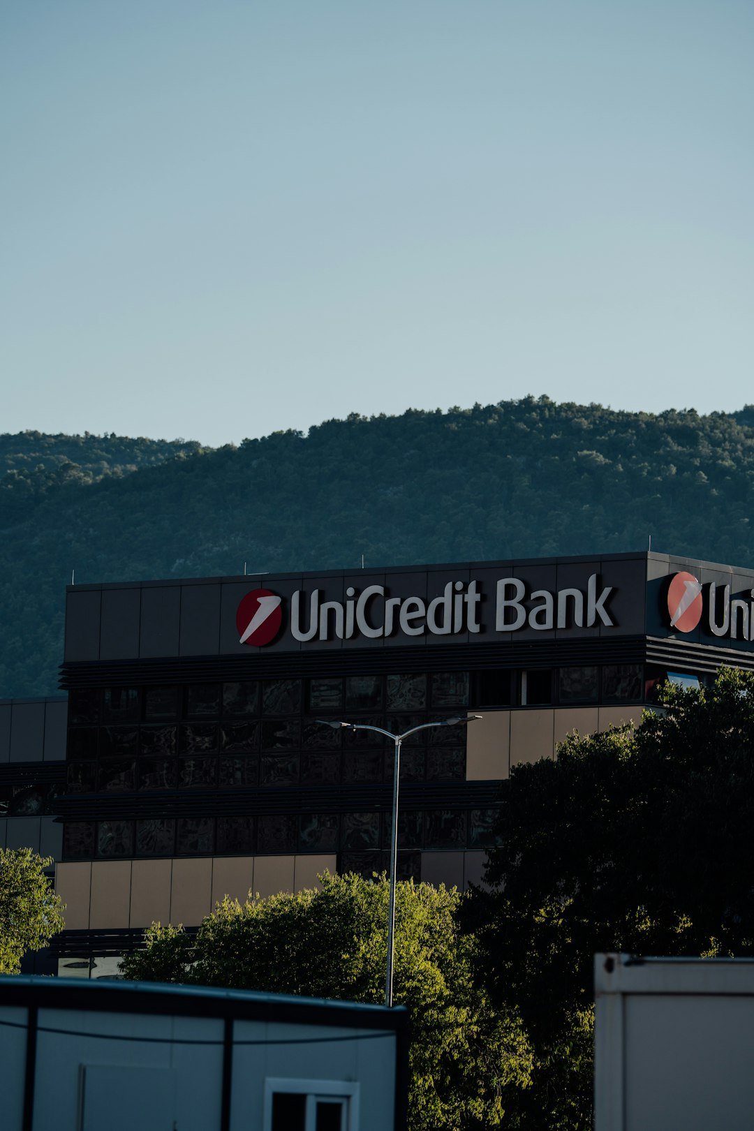 Unicredit bank building with trees and hills