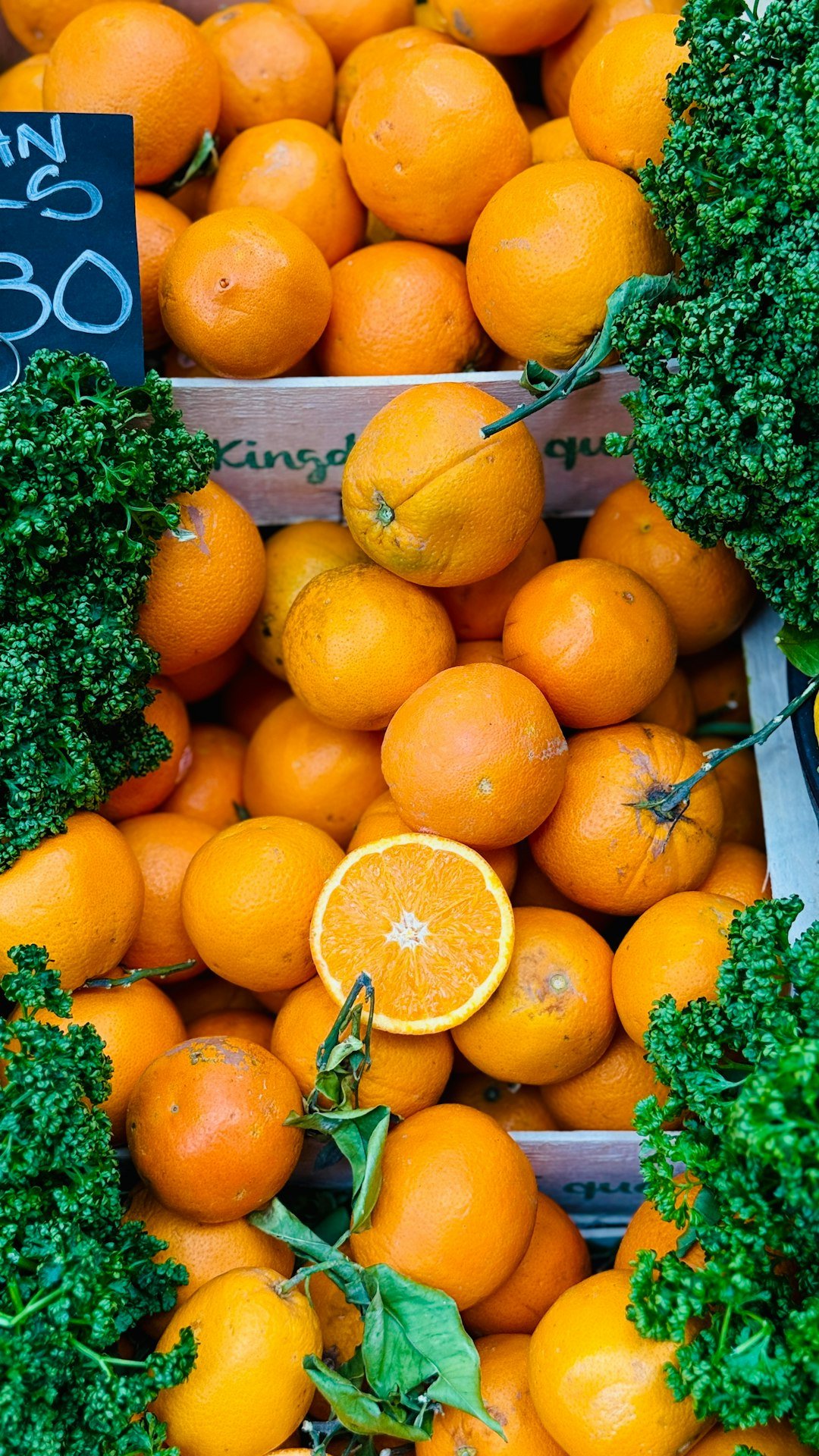 Fresh oranges and greens are ready for sale.