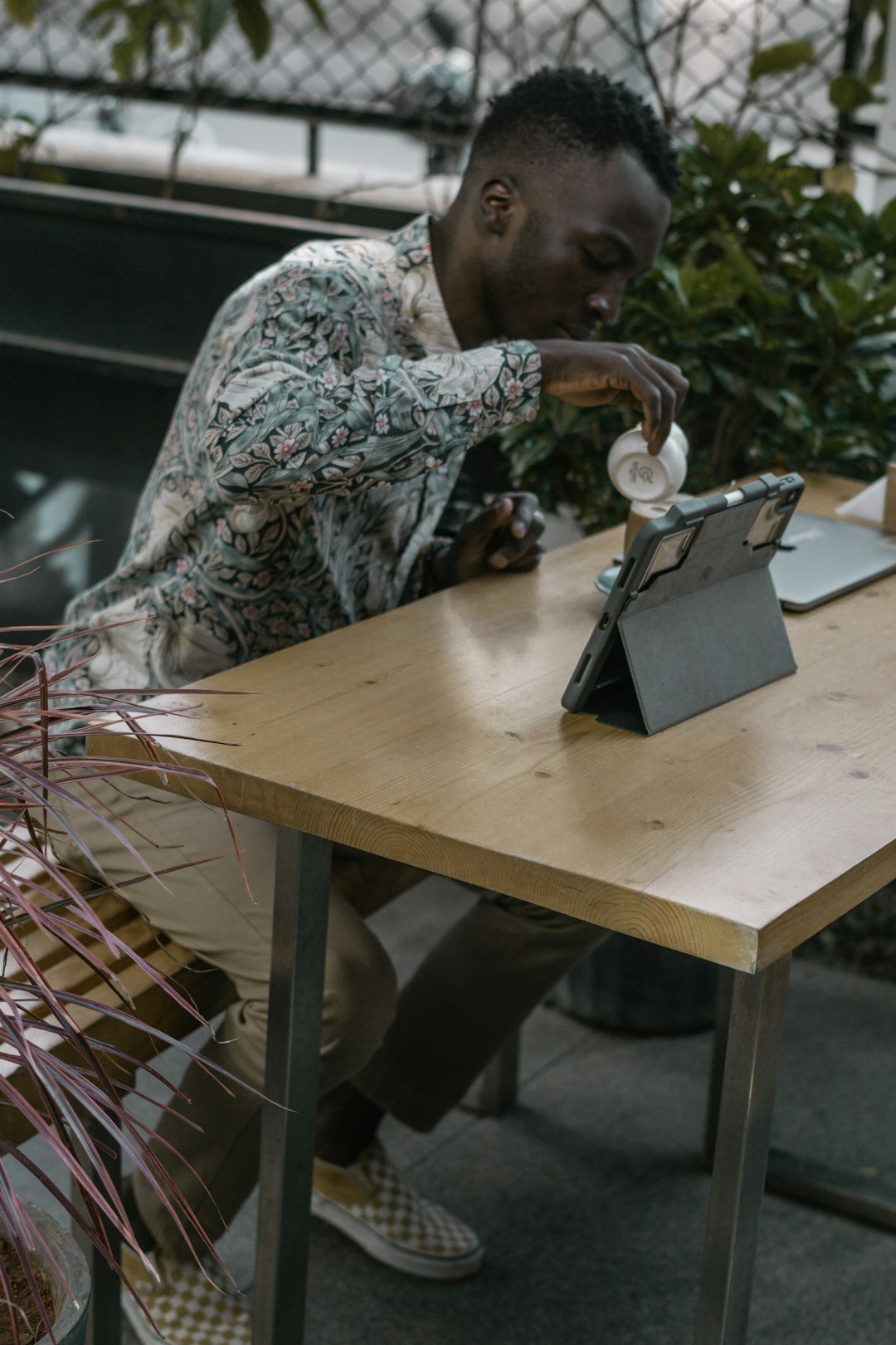 man pouring in cup while sitting near table