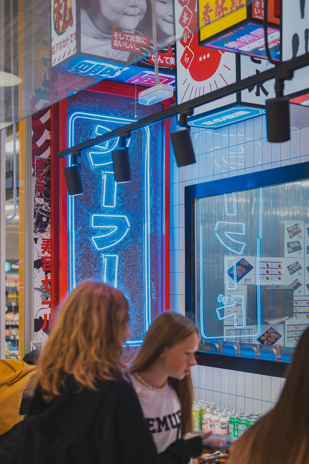 Neon signs illuminate people in a japanese restaurant.
